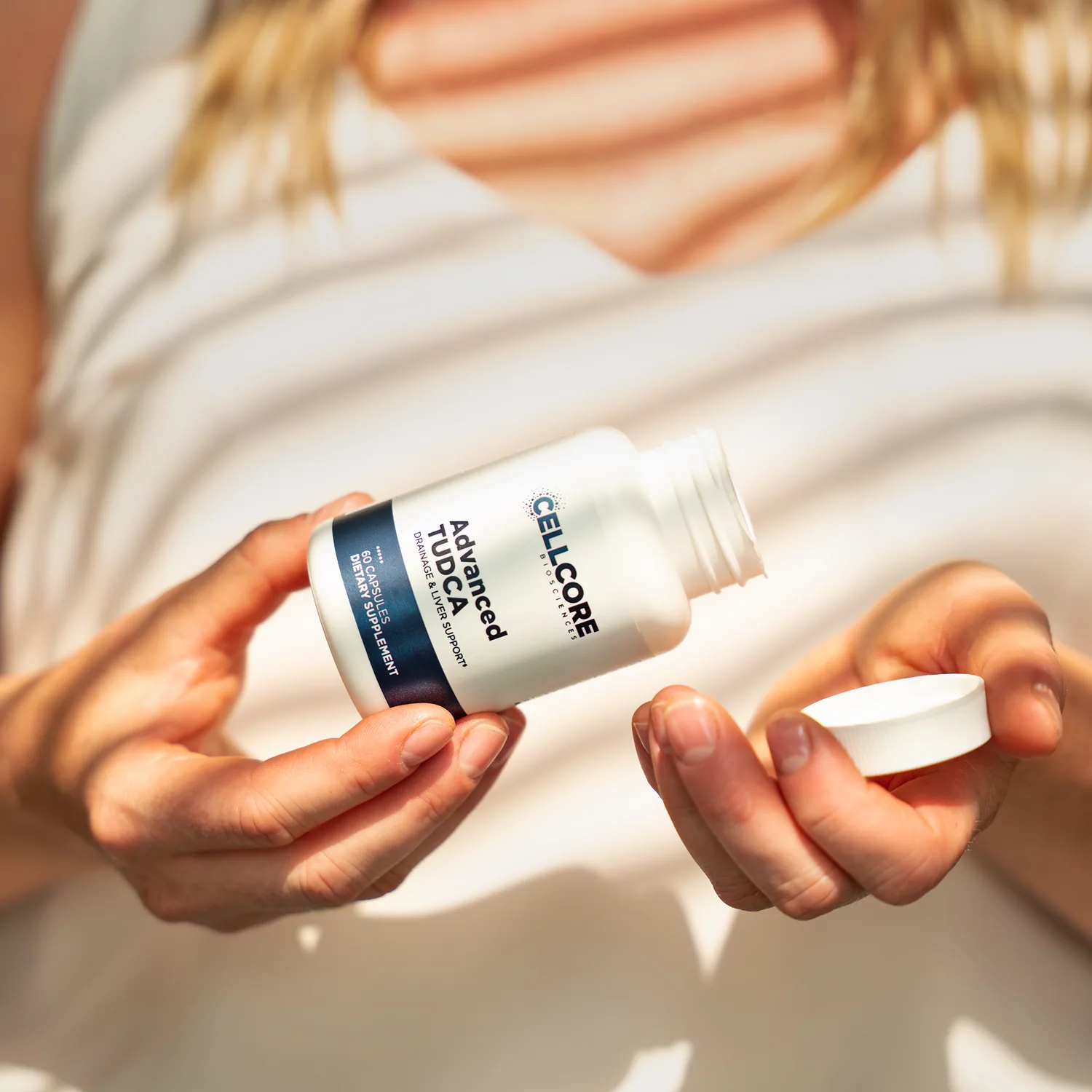 Woman opening a bottle of Advanced TUDCA drainage and liver support capsules