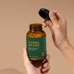 Hands opening a bottle of Global Healing Candida Balance capsules
