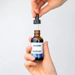 Hands holding the HydrOxygen dropper bottle and lifting the dropper out