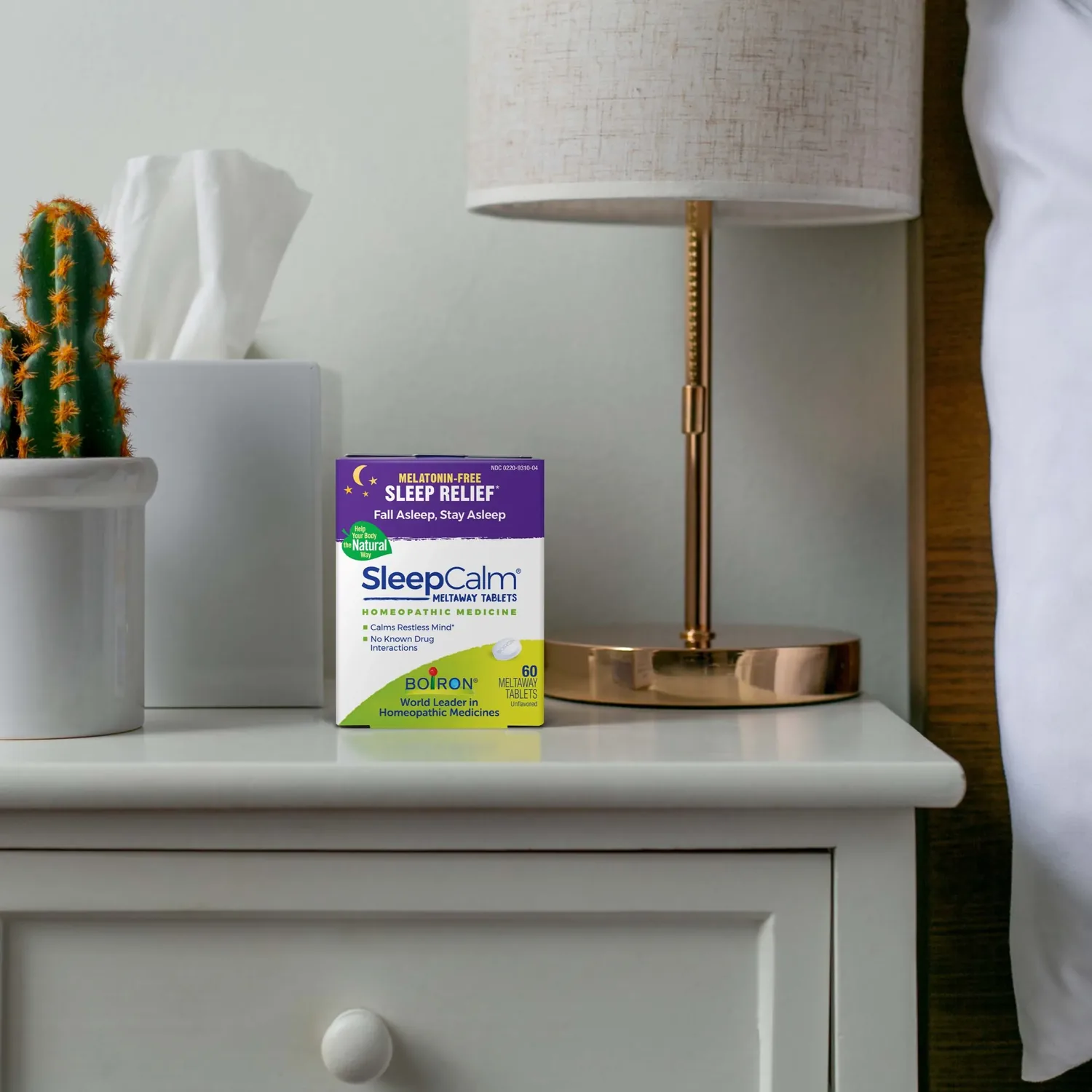 Boiron SleepCalm box on a bedside table beside a lamp, showing the size of the 60-tablet pack